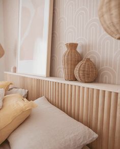 two vases sitting on top of a shelf next to pillows