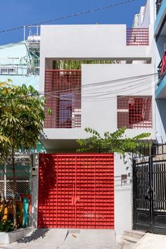 a red gate is in front of a white and blue building with two balconies