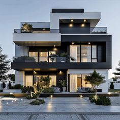 a modern house with lots of windows and balconies on the second floor, lit up at night