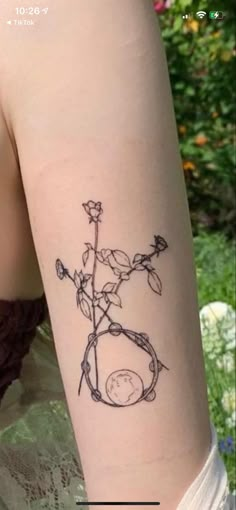 a woman's arm with a tattoo on it that has flowers and vines growing out of it