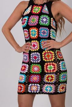 a woman wearing a multicolored crochet dress with her hands on her hips