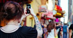 a woman taking a photo with her cell phone on the street in front of people