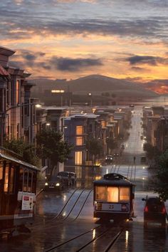 a trolley car is driving down the street in the rain at dusk with its lights on