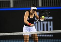 a woman holding a tennis racquet on top of a tennis court with a ball in her hand