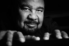 a black and white photo of a man with his hands on the edge of a table