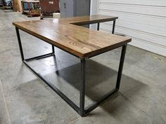 two tables made out of wood and metal in a warehouse area with garage doors behind them