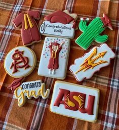 decorated cookies are arranged on a plaid tablecloth with the words congrats grad