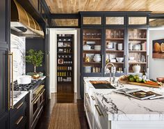 a kitchen with marble counter tops and black cabinets, along with wooden ceilinging that matches the wood paneled ceiling