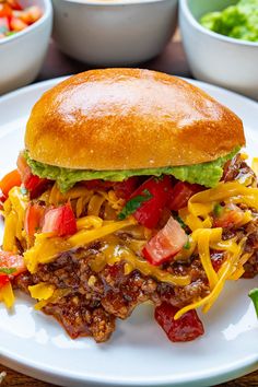 a white plate topped with a sandwich covered in cheese and toppings next to bowls of salad