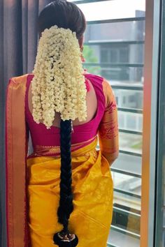 the back of a woman's head wearing a yellow sari with flowers in her hair