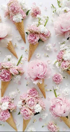 ice cream cones filled with pink flowers and white carnations on a white surface