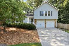 a white house with two garages and trees in the front yard on a sunny day