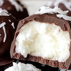 chocolate covered coconuts with white frosting on top and one cut in half to show the inside