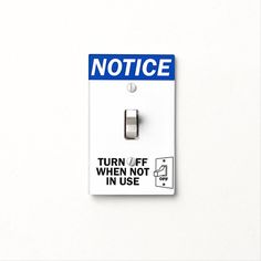 a white light switch with a blue notice sticker on it