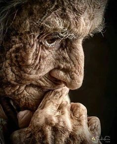 an old woman with wrinkles holding her hands to her face