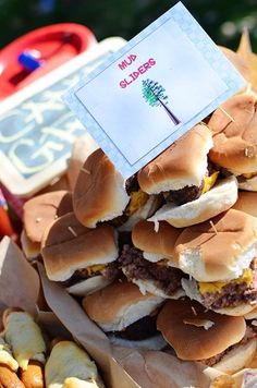 a pile of hamburgers sitting on top of a table next to other food items