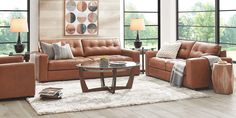 a living room filled with brown furniture and windows