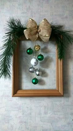 an ornament hanging on the wall in a frame decorated with pine branches and ornaments