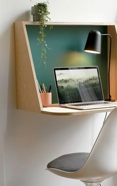 an open laptop computer sitting on top of a wooden shelf next to a white chair