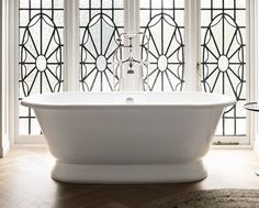 a large white bath tub sitting next to two windows with stained glass panels on them