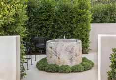 an outdoor fountain surrounded by shrubbery and chairs