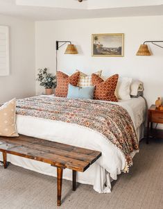 a bed sitting in a bedroom next to a wooden table and two pictures on the wall