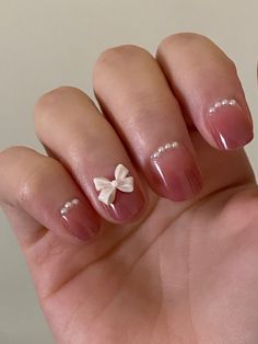 a woman's hand with french manies and a bow on the tip of her nails