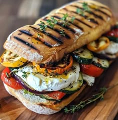 a sandwich with meat, cheese and vegetables on it sitting on a wooden cutting board