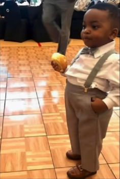 a little boy standing on the floor holding an apple