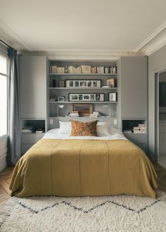 a large bed sitting in a bedroom next to a tall book shelf filled with books