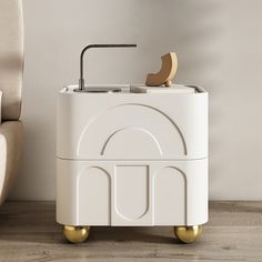 a white cabinet with a sink and faucet on wheels in front of a beige chair