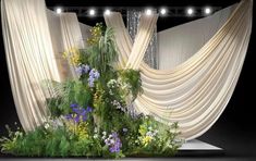 a stage with curtains and flowers on it