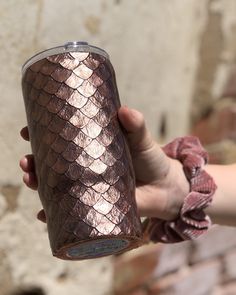 a person holding a pink colored drink in their left hand and brick wall behind them