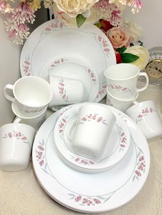 a table topped with lots of white plates and cups