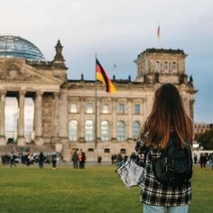 a woman standing in front of a building with a german flag on it's side