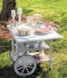 a table that has some desserts on top of it in front of a tree