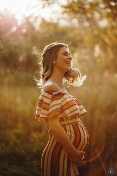 a pregnant woman is standing in the woods with her hands on her hips and looking off to the side