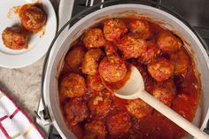 a large pot filled with meatballs and sauce next to a white plate full of food