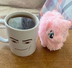 a pink stuffed animal next to a coffee cup