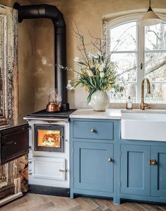 a stove top oven sitting inside of a kitchen next to a sink and wooden floors