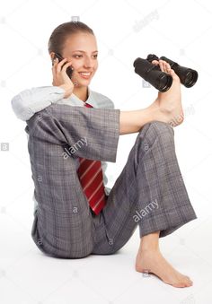 a woman sitting on the ground talking on a cell phone and holding binoculars in her hand