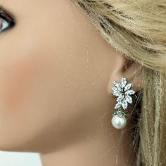 Add a touch of feminine elegance to your bridal ensemble with these shimmering floral-inspired earrings. Featuring delicate cubic zirconia leaves and simulated ivory pearls, these earrings exude timeless charm and sophistication. Measuring 1.5" in length and 3/4" in width, these earrings are lightweight and comfortable for your special day. Crafted with high-quality materials, including Cubic Zirconia and simulated pearls, they offer beauty and durability. Finished with lead, nickel, and cadmium Classic Cubic Zirconia Flower Earrings For Wedding, Classic Wedding Flower Earrings In Cubic Zirconia, Classic Wedding Flower Earrings With Cubic Zirconia, Elegant Pear-shaped Pearl Earrings With Diamond Accents, Elegant Bridal Flower-shaped Pearl Drop Earrings, Classic Pear-shaped Pearl Earrings With Cubic Zirconia, Formal Flower-shaped Bridal Earrings With Pearl Drop, Pearl-embellished Cubic Zirconia Drop Earrings, Metal Hair Accessories