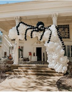 a house decorated for halloween with white and black balloons in the shape of a spider