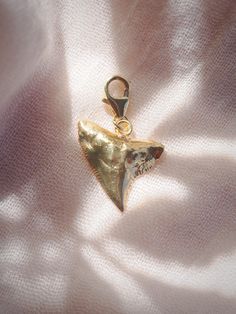 Add to your collection with this Genuine Shark Tooth Charm completely plated in gold. Choose from a regular jump loop or lobster clasp to make it your own and attach to any existing jewelry. Planning on purchasing a chain for this and need help attaching it? Let us know and leave a note during checkout! This item will arrive separate/detached if no note is left.✦ DETAILS ✦✧ Gold plated Genuine Shark Tooth.✧ 14kt Gold Filled Loop or Clasp.✧ Chains sold separately.✧ All Ke Aloha Jewelry pieces com Yellow Gold-plated Charms With Lobster Clasp, Yellow Gold Charms For Jewelry Making, Gold Charms With Lobster Clasp For Jewelry Making, Yellow Gold Charms With Lobster Clasp For Jewelry Making, Gold Heart Dangle Charms, Gold Dangle Heart Charms, Gold-tone Metal Charms For Gifts, Gold Heart Metal Charms, Gold Heart-shaped Metal Charms