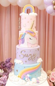 a three tiered cake decorated with unicorns and rainbows is on top of a table