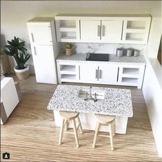 a model kitchen with white cabinets and marble counter tops, two stools at the center