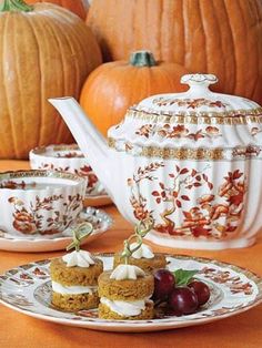 pumpkins are in the background with tea cups and dessert dishes on top of them