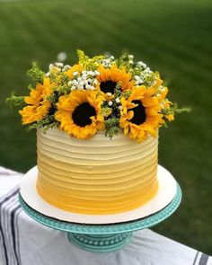 a cake with sunflowers and baby's breath on top is sitting on a table