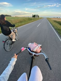 a person riding a bike down the middle of a road next to another person on a bicycle