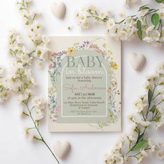 a baby shower with flowers and hearts on the side, next to it's birth announcement card